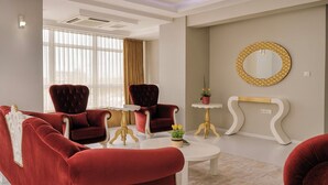 A modern living room with red velvet sofas, a white coffee table, and a gold-framed mirror on the wall.