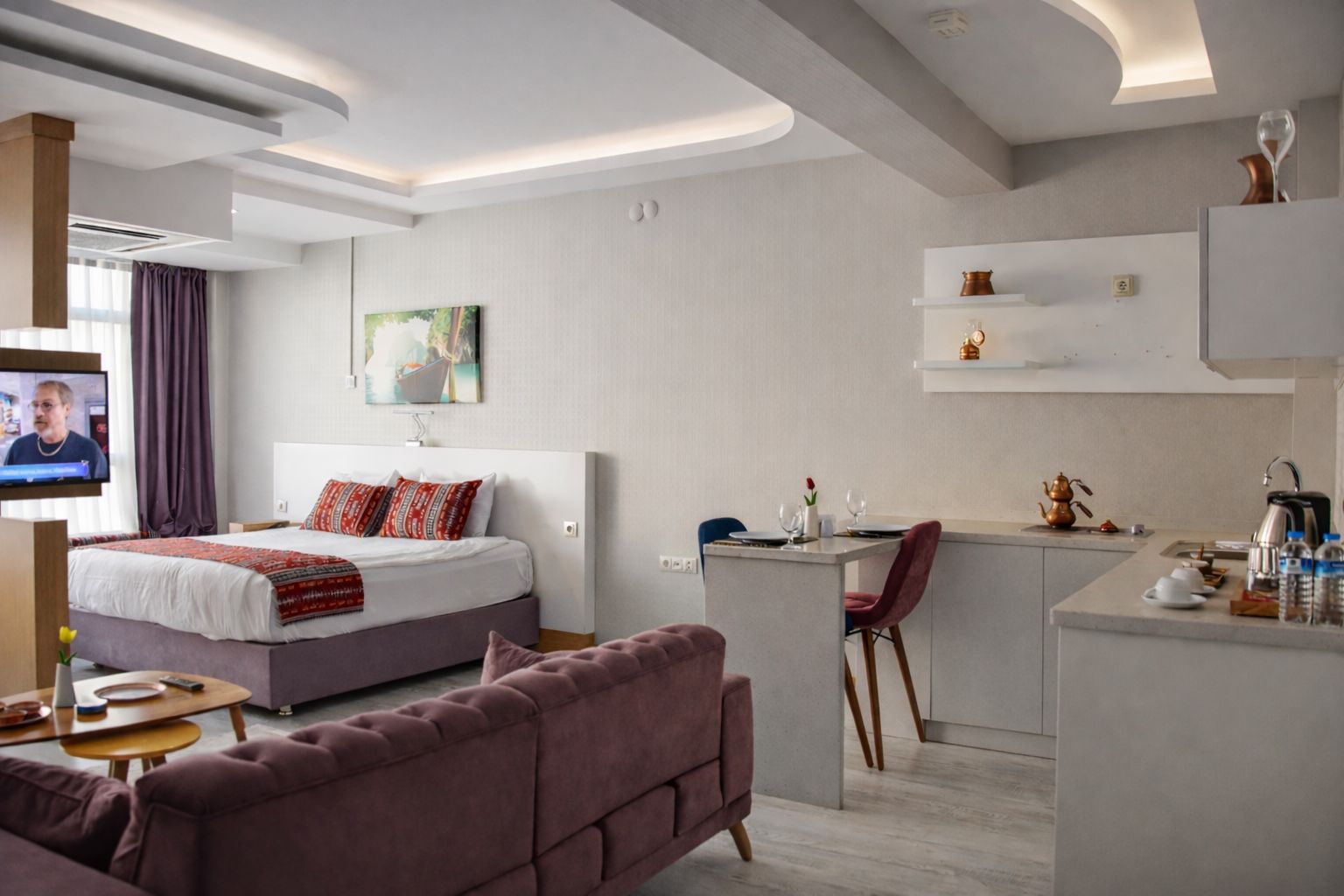 Una habitación de hotel moderna con cama, sofá, escritorio y kitchenette.
