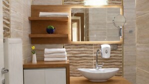 A modern bathroom with a wooden vanity, a sink, a mirror, and a towel rack.