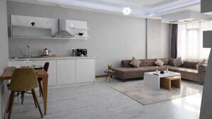 A modern living room with a sofa, coffee table, and a dining area with a table and chairs.