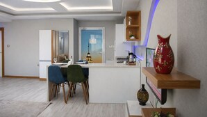 A modern interior with a dining area, kitchen, and a decorative shelf with a vase.