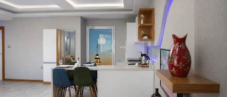 A modern interior with a dining area, kitchen, and a decorative shelf with a vase.