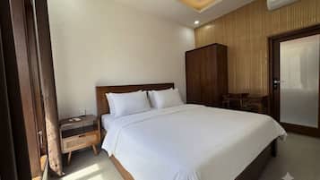 A hotel room with a large bed, a wooden wardrobe, a nightstand, and a door with a handle.