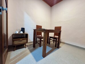 A corner room with a wooden table and chairs, a small cabinet with a radio, and a plain wall. - Galang Homestay Ubud - Peaceful Balinese Retreat (Gianyar)