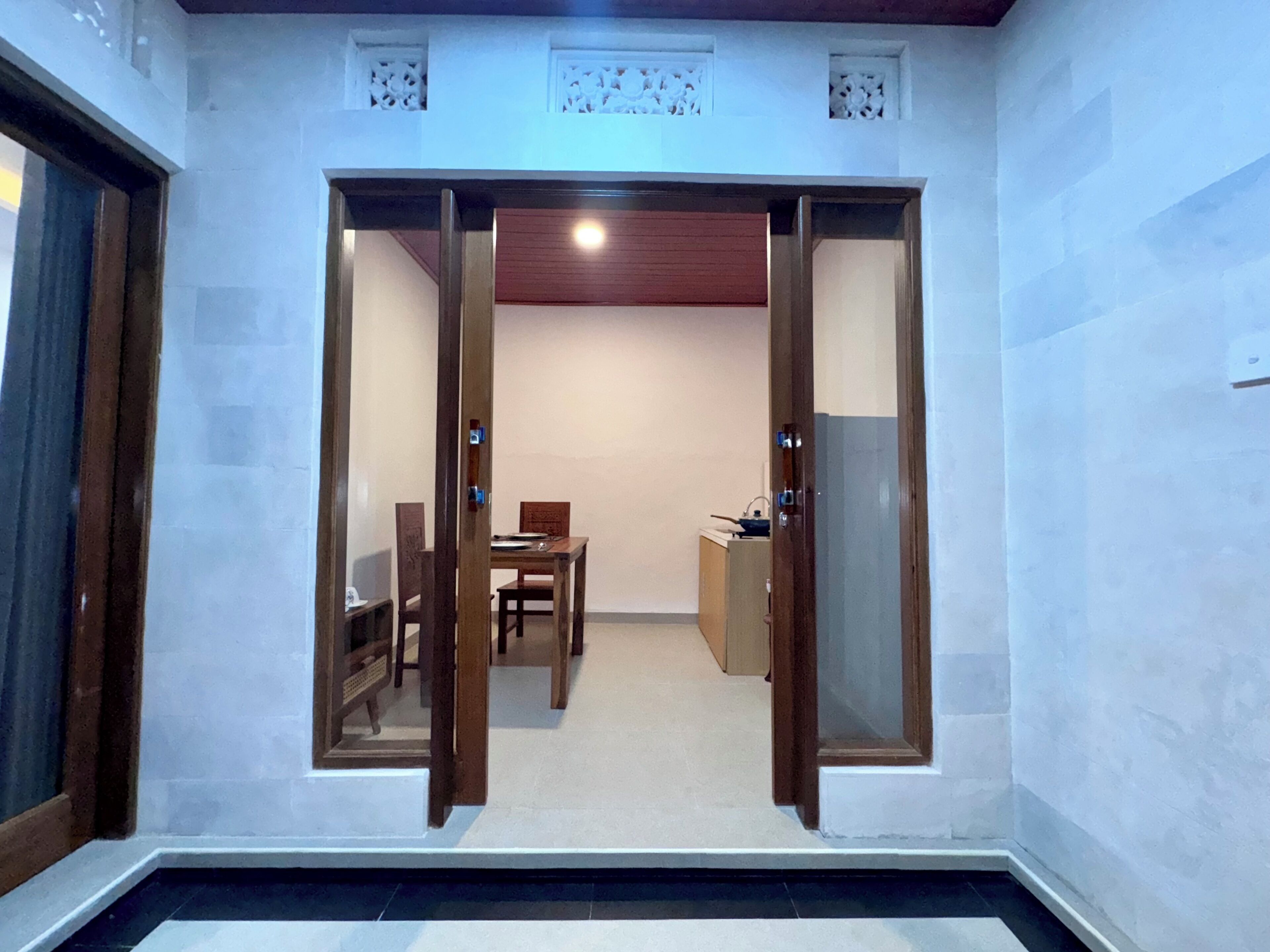 A room with a wooden door leading to a dining area with a table and chairs.