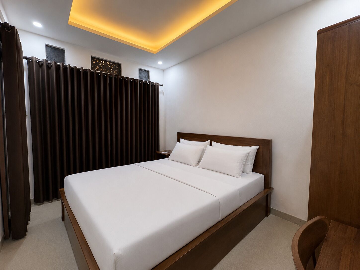 A modern bedroom with a large bed, wooden headboard, and a ceiling light fixture.