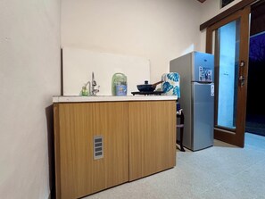 A compact kitchen with wooden cabinets, a sink, a stove, and a refrigerator. - Galang Homestay Ubud - Peaceful Balinese Retreat (Gianyar)