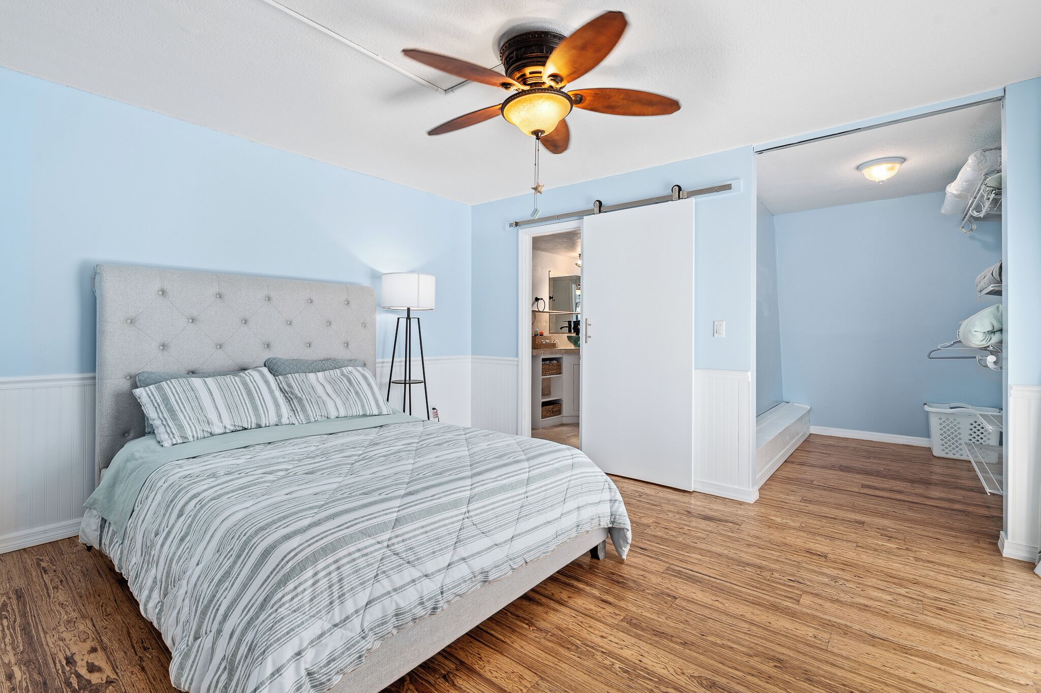 A bedroom with a bed, a ceiling fan, a nightstand, and a walk-in closet.