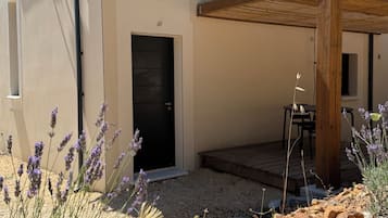 Ein modernes Gebäude mit einer schwarzen Tür, einem kleinen Fenster und einer Holz-Pergola.