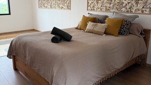 A bedroom with a large bed, a window, and two wall-mounted artworks.