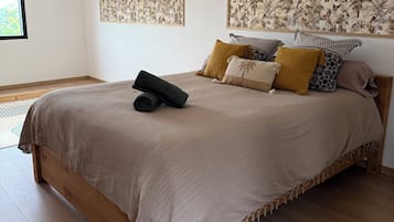 Een slaapkamer met een groot bed, een raam en twee kunstwerken aan de muur.