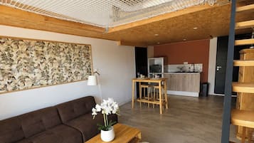 A modern living room with a sofa, a wooden coffee table, and a dining area with a table and chairs.