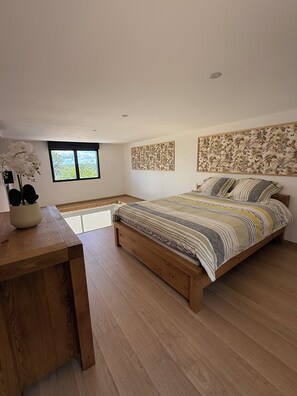 A bedroom with a wooden bed, a window, and a wall-mounted artwork. - The Hanging Nest & SPA (Saint-Martin-de-Valgalgues)