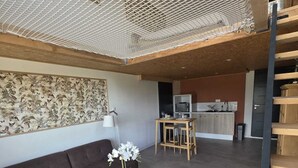 A modern living space with a sofa, a wooden coffee table, and a dining area with a kitchen in the background.