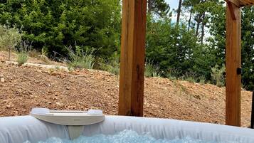 Een hottub onder een houten pergola, met een natuurlijk landschap op de achtergrond.