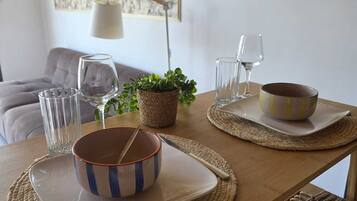 Una mesa de comedor dispuesta con platos, tazones, vasos y una planta.