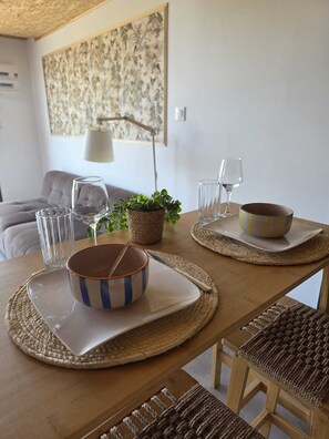 A dining table set with plates, bowls, glasses, and a plant. - The Hanging Nest & SPA (Saint-Martin-de-Valgalgues)