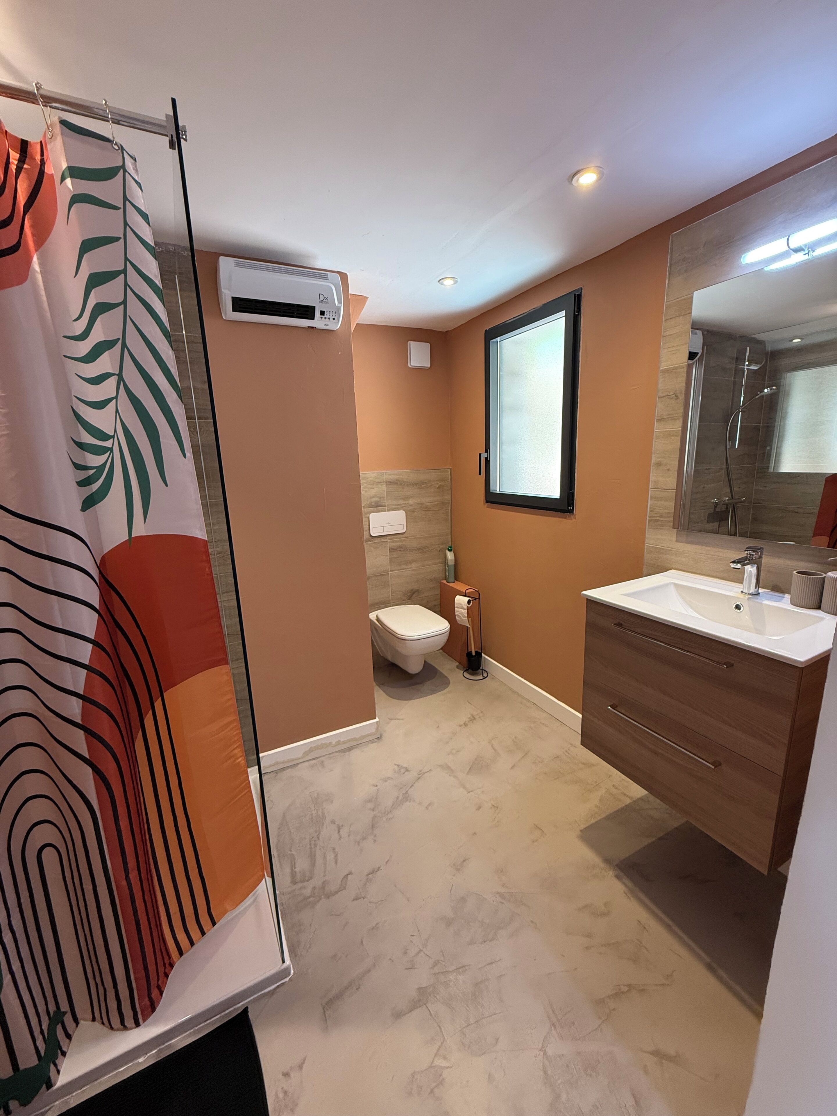 Een badkamer met douche, toilet en wastafel met spiegel.
