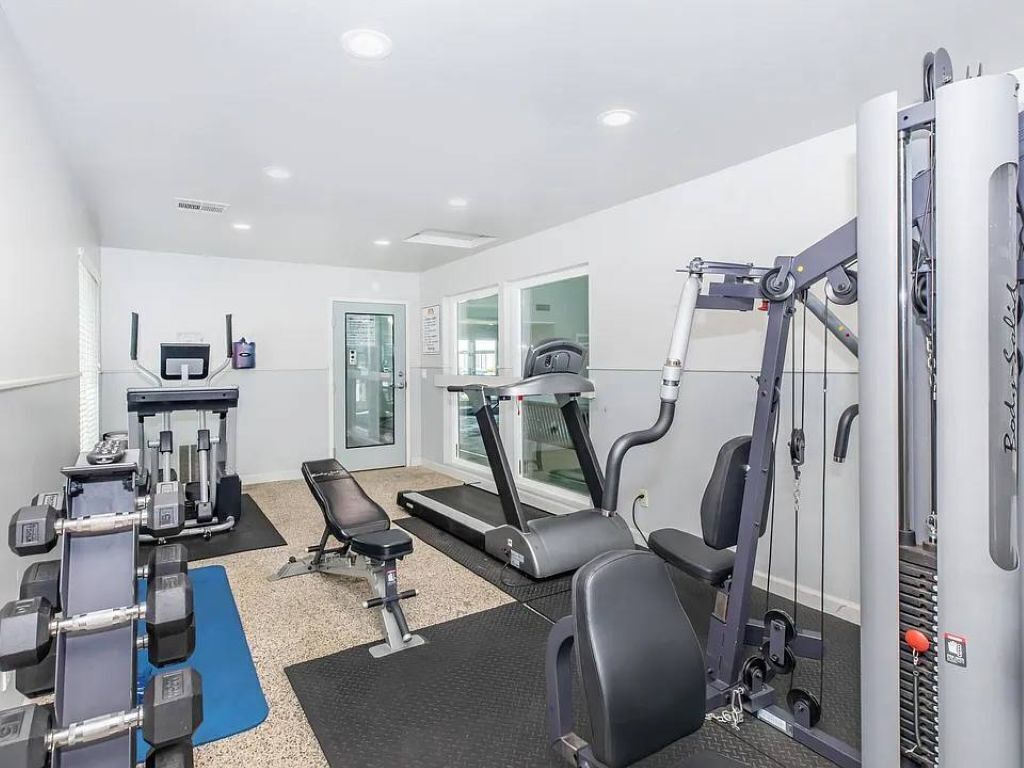 A gym with exercise equipment, a treadmill, and a bench.