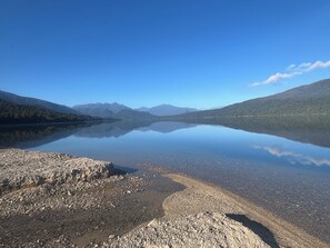 Un lac paisible, bordé d’une rive rocheuse, avec des montagnes en arrière-plan.