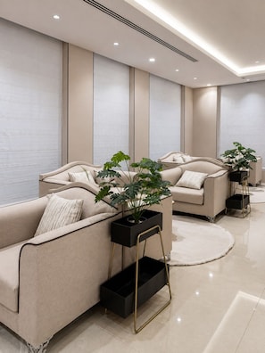 Uma sala de estar moderna com um sofá bege, uma mesa lateral preta e um vaso com planta.