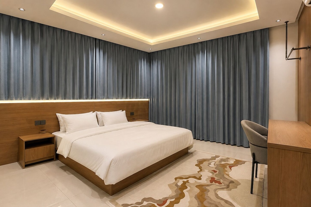 Quarto de hotel moderno com uma cama grande, uma escrivaninha e uma cadeira.