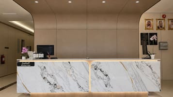 En receptionsdisk med en marmorskiva, en digital display och en skylt med texten ”RECEPTION”.