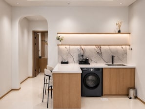 Cozinha moderna com máquina de lavar embutida, painel de fundo de mármore e design minimalista.