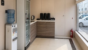 Une cuisine moderne équipée d’un distributeur d’eau, d’une machine à café et d’un espace dédié à la préparation du café.