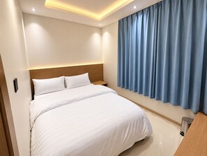 A hotel room with a bed, a nightstand, a trash bin, and a window with curtains. - Meada Residence  (Riyadh)