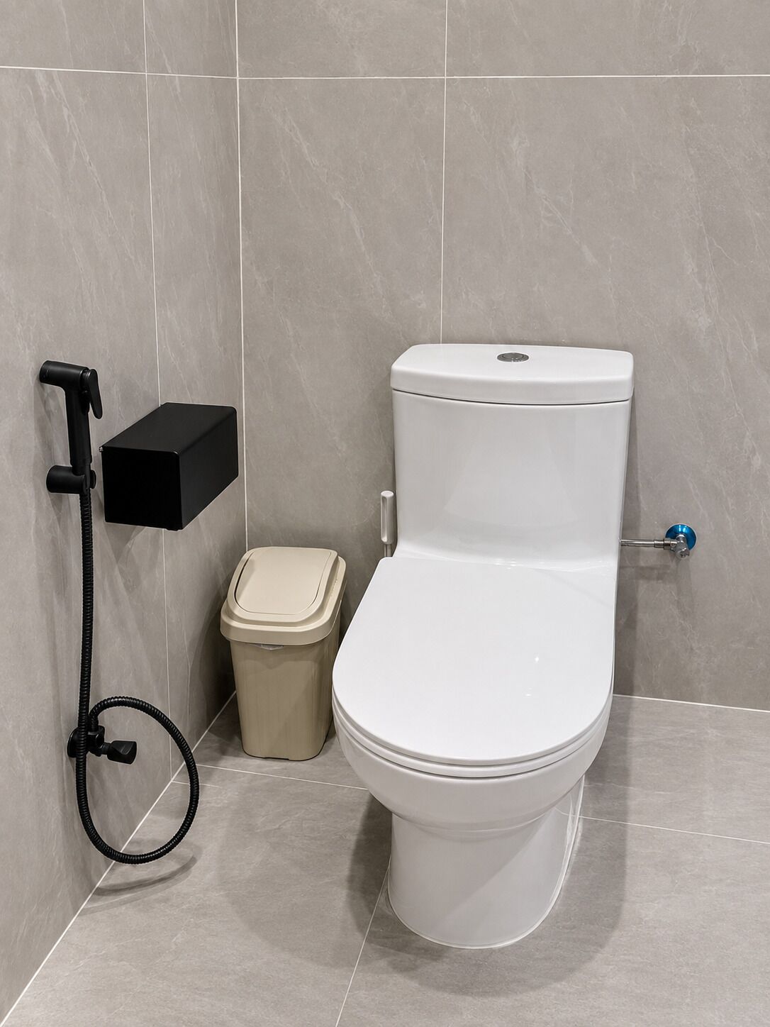 Een moderne badkamer met een toilet, een prullenbak en een douchecabine.