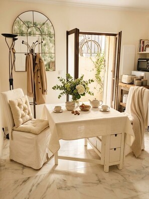 Una habitación con una mesa preparada para tomar té, una silla, un espejo y vistas al exterior.