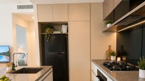 A modern kitchen with a built-in dishwasher, a black refrigerator, and a stove. - The Riverglass Retreat | Brisbane Skyline Escape (Brisbane City)