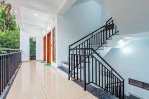 Un interior moderno con una escalera, un pasillo y una puerta que da a un área verde.