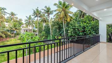 A corridor with a view of a lush garden with palm trees and a tiled floor.