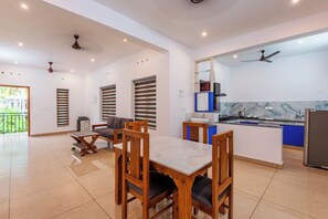 Una cocina moderna con salpicadero de mármol, un comedor con mesa y sillas de madera, y un balcón con vistas.