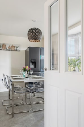 A modern kitchen with a central island, stainless steel appliances, and a hanging pendant light. - Five separate bedrooms on a quiet cul-de-sac in NR4, minutes from the A47. A room each for a team of five, or sleeps up to 9 when couples share. Open-plan kitchen the full depth of the house, driveway parking for three and 293 Mbps WiFi. (Norwich)