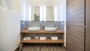 A modern bathroom with two sinks, a mirror, and a wooden vanity.