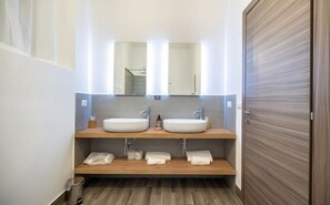 A modern bathroom with two sinks, a mirror, and a wooden vanity.