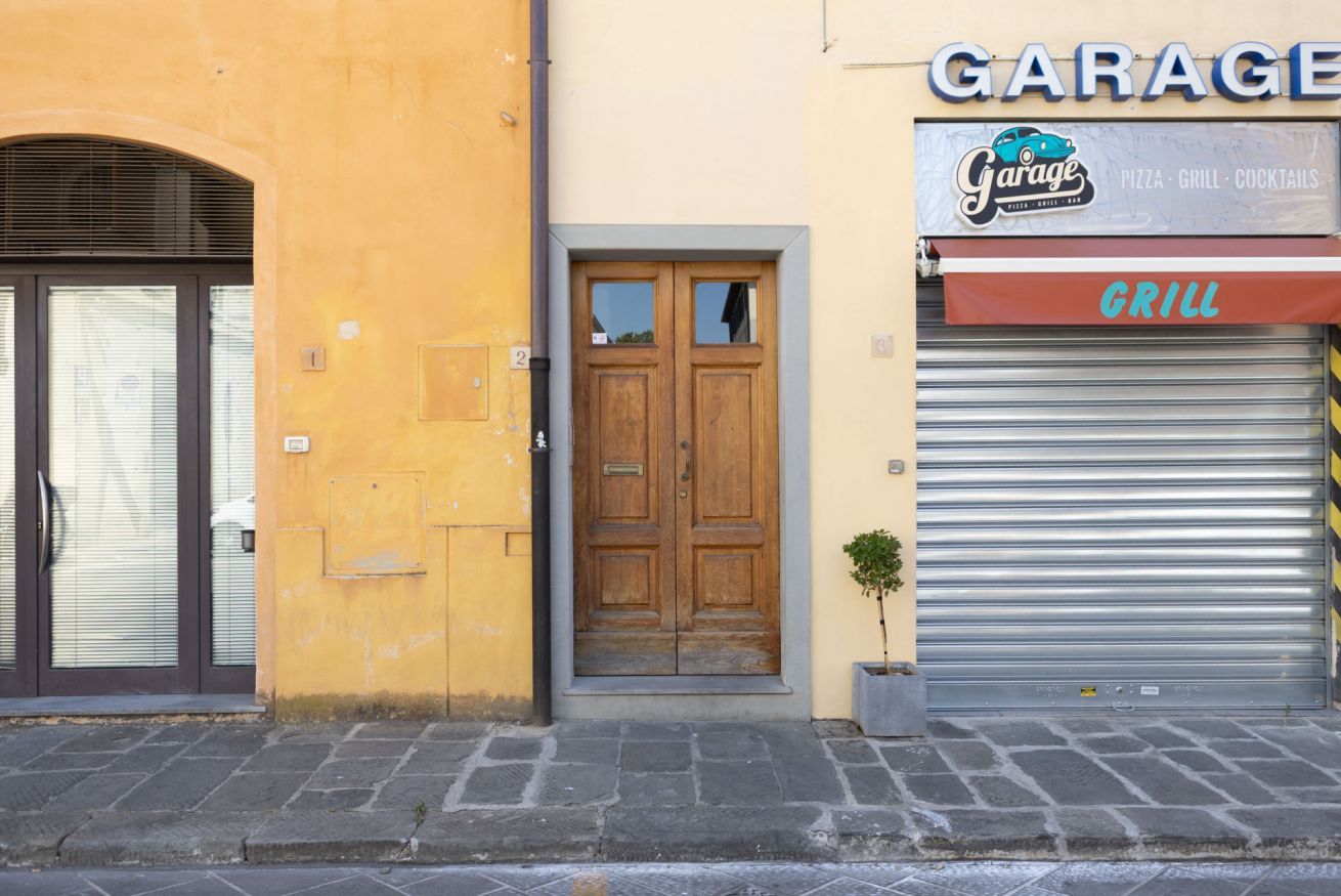 A building facade with a garage sign, a wooden door, and a closed metal shutter.