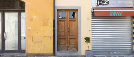 Fachada de edificio con un letrero de garaje, una puerta de madera y un persiano metálico cerrado.