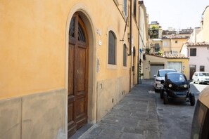 A narrow street with a yellow building, a wooden door, and parked cars. - San Frediano Central Stay (Florence)