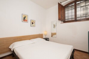 A room with a bed, a nightstand, a lamp, a mirror, and two framed pictures on the wall. - San Frediano Central Stay (Florence)
