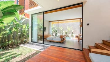 Un interior moderno con cubierta de madera, un vidrio que da a una zona de estar y vistas a un jardín.