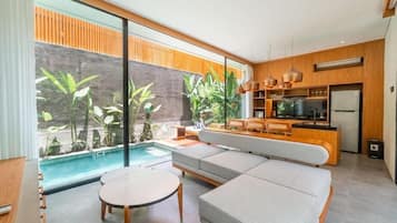 A modern living room with a pool, a sofa, and a dining area.