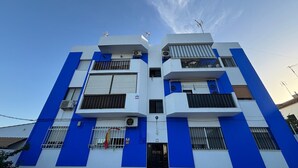 Un edificio de varios pisos con fachada plana, balcones y unidades de aire acondicionado.