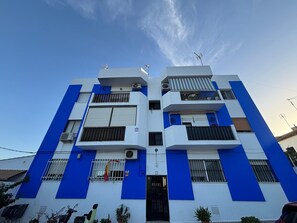Ein mehrstöckiges Gebäude mit flacher Fassade, Balkonen und Klimaanlagen.