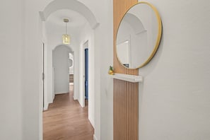 A hallway with wooden flooring, white walls, and a round mirror with a gold frame on a wooden shelf. - Apartment 'Brisa del Sur' (Isla Canela) for 6 guests, Huelva & Portugal, Wi-Fi, A/C and bright (Ayamonte)