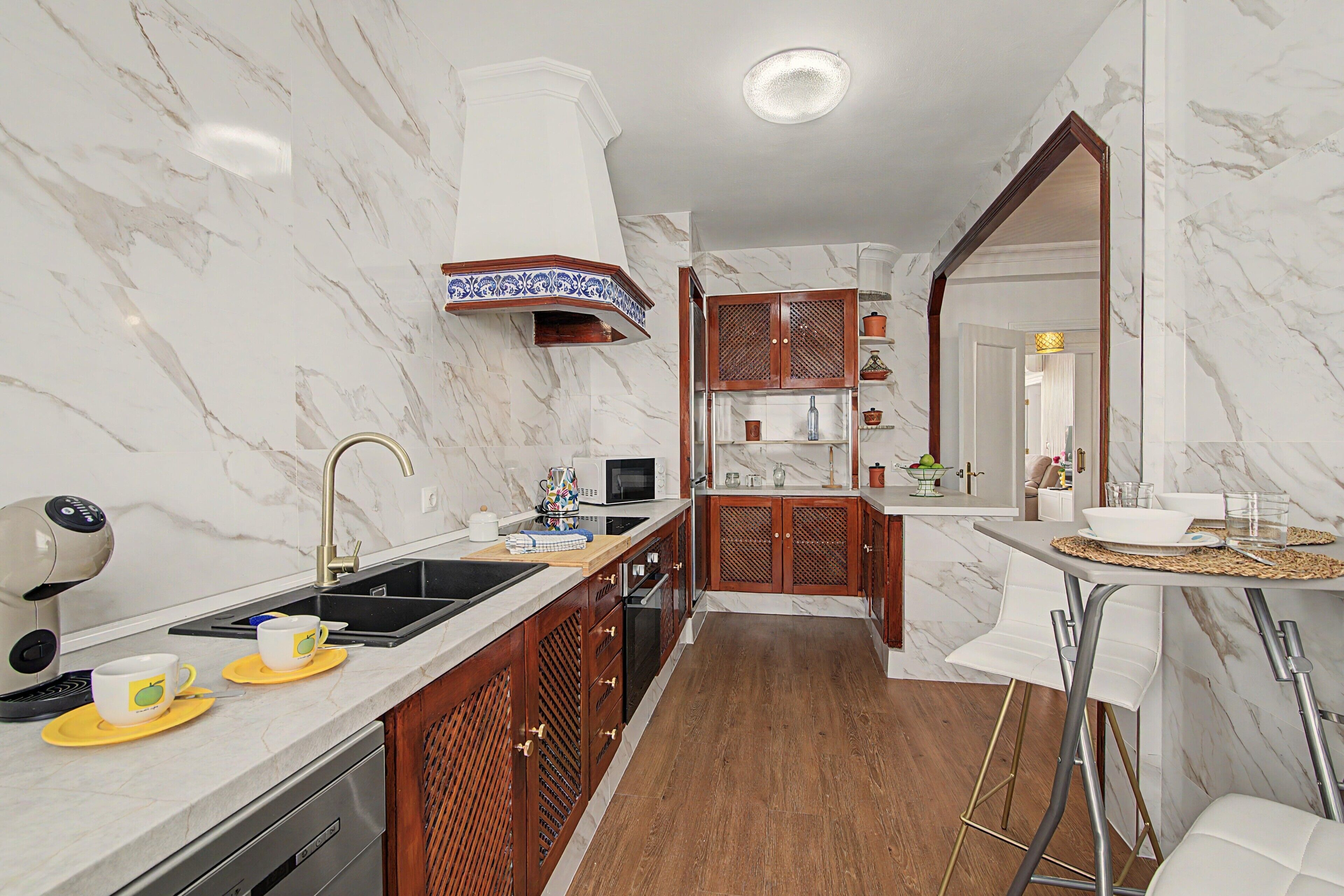 A modern kitchen with marble walls, a wooden cabinet, and a built-in oven.
