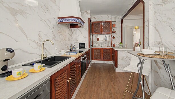 Una cocina moderna con paredes de mármol, un armario de madera y un horno empotrado.